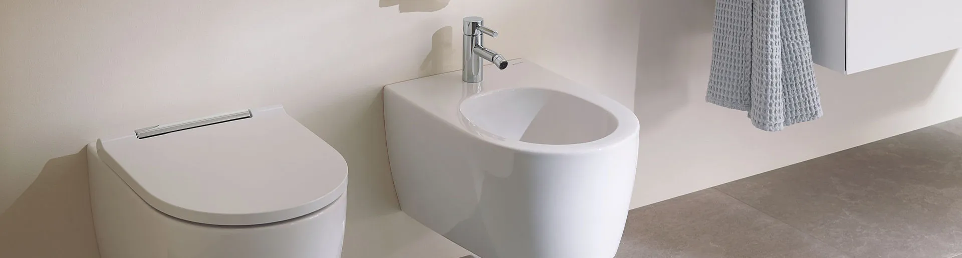 Detailaufnahme eines stilvoll eingerichteten Badezimmers mit einer weißen Hänge-Toilette und einem dazugehörigen Bidet. 