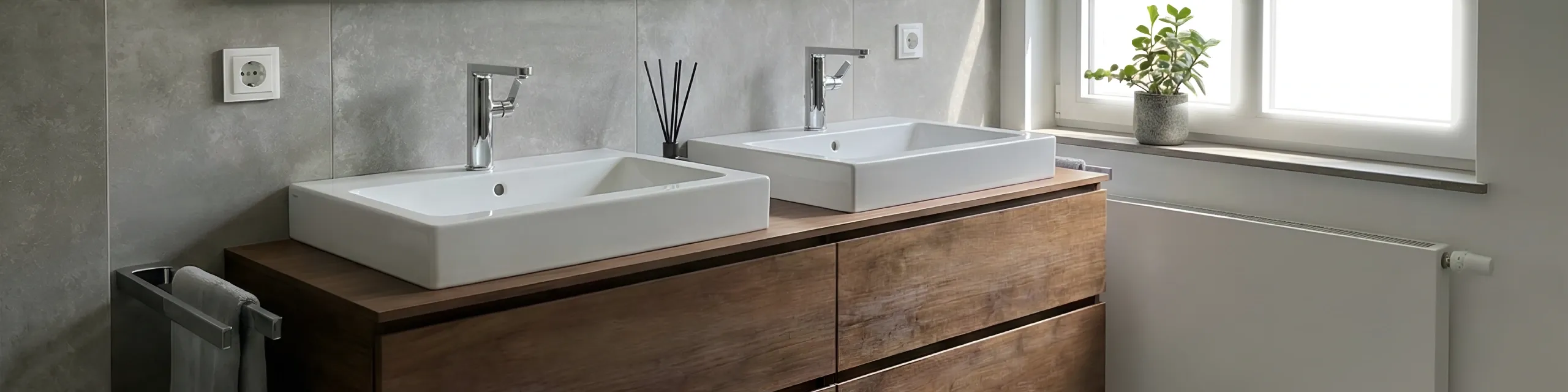 Hochwertiges Badezimmer mit zwei weißen Waschbecken, Chromarmaturen und Fensterbank mit Zimmerpflanze.