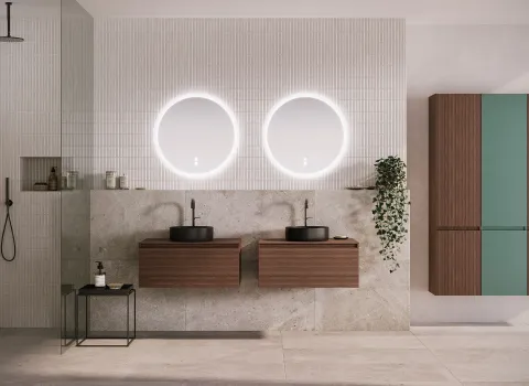 Minimalistisches Bad mit eleganten Holzmöbeln, beleuchteten Spiegeln und schwarzen Akzenten. Die schwebenden Schränke der Serie Lin20 von burgbad und klare Linien betonen das aufgeräumtee Design.