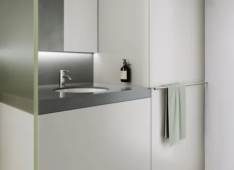 Ein minimalistischer Waschtisch mit chromglänzender Armatur und glatter grauer Oberfläche.