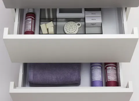 Zwei offene Schubladen eines weißen Badezimmerschranks zeigen eine ordentliche Anordnung von Pflegeprodukten. 