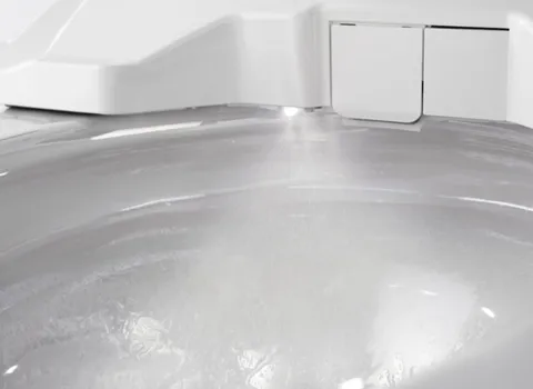 Ein Dusch-WC in Aktion, bei dem ein feiner Wasserstrahl in die Toilettenschüssel sprüht.