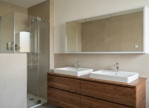 Zeitloses Bad mit zwei Waschbecken, Spiegelschrank und natürlichem Holzdekor.