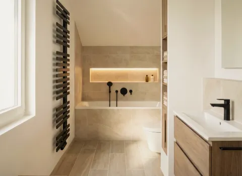 Zeitgemäßes Bad mit freistehender Badewanne, beleuchtetem Wandregal und schwarzer Sanitärtechnik.