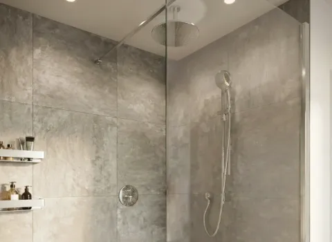 Stylische Dusche mit grauen Fliesen, Edelstahlarmaturen und integrierter Regendusche.