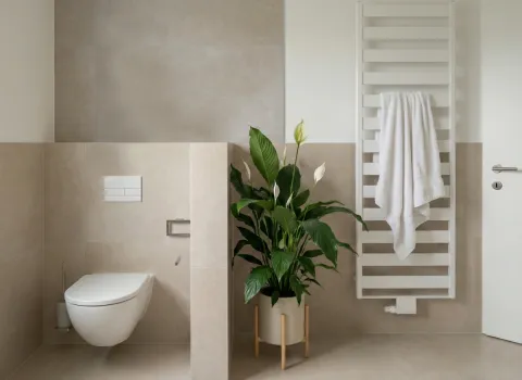 Toilettenbereich im Bad mit beigen Fliesen, wandhängendem WC und Handtuchwärmer neben Tür.