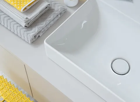 Detailaufnahme eines rechteckigen Keramik-Waschbeckens von Duravit mit Handtüchern und Badaccessoires.