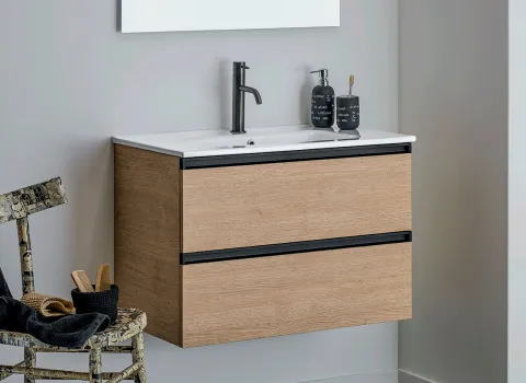 Kompaktes Stocco Badmöbel mit heller Holzfront, schwarzer Griffleiste und weißem Waschbecken in modernem Design.