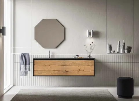 Modernes Badezimmer mit schwebendem Waschtisch in Holzoptik, schwarzer Waschtischplatte und geometrischem Wandspiegel.