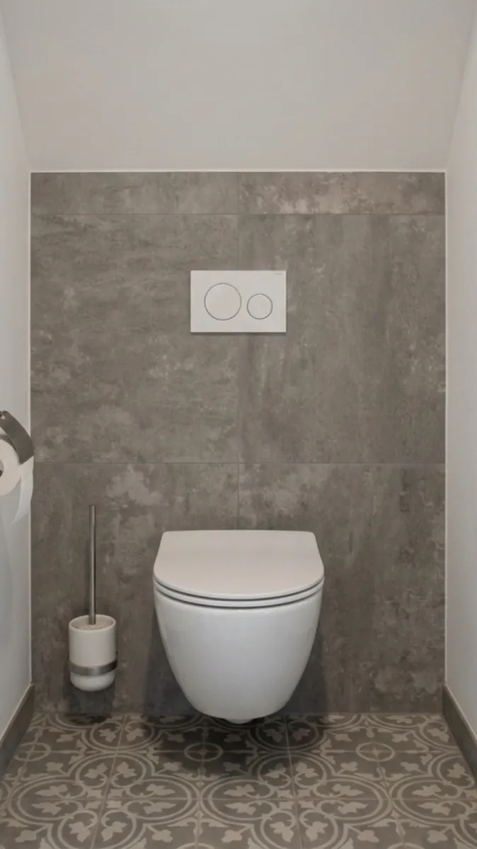 Stilvoll eingerichtetes Gäste-WC mit platzsparender Hängetoilette, dunklen Wandfliesen und Designboden.