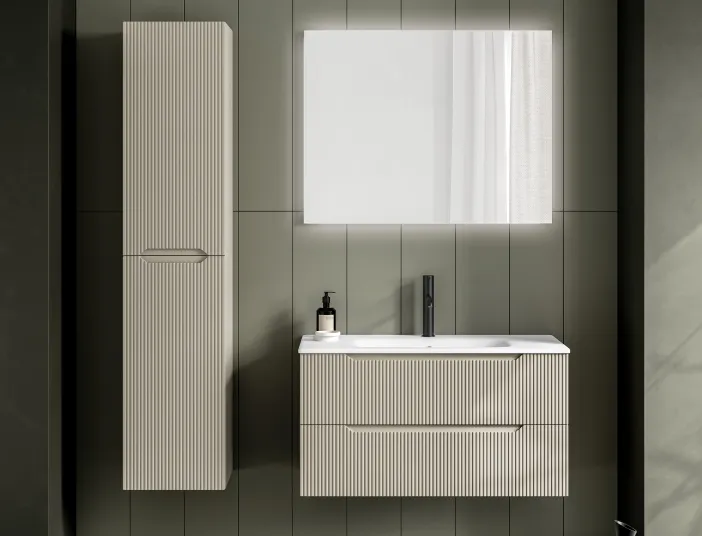 Badmöbel mit geriffelter Front in Elfenbein und passendem Hochschrank vor grüner Wand.